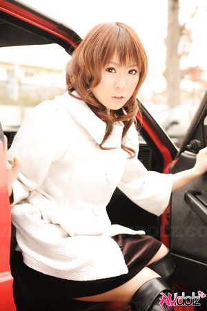 Asian Yuko Morita in white coat and long boots poses in her car.