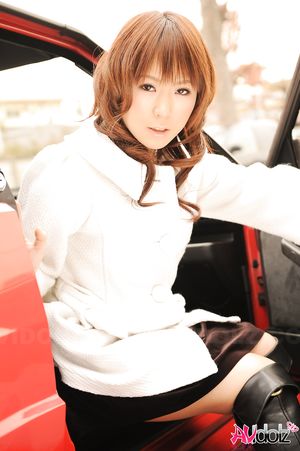 Asian Yuko Morita in white coat and long boots poses in her car.