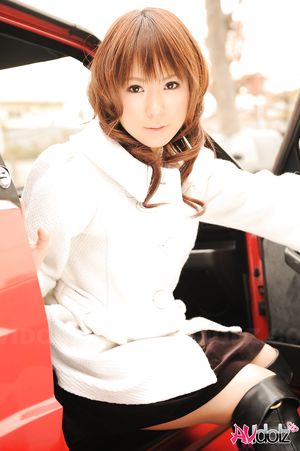 Asian Yuko Morita in white coat and long boots poses in her car.