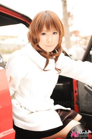 Asian Yuko Morita in white coat and long boots poses in her car.