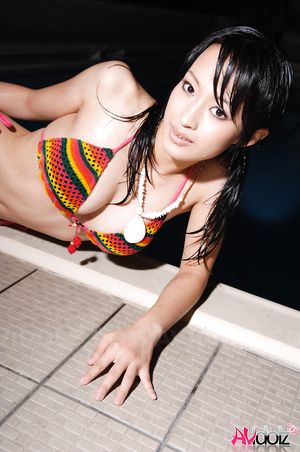 Busty Mio Kanna poses in a colorful bath suit next to the pool.