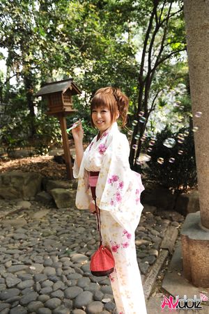 Asian Ichika in a beautiful kimono makes some soap bubbles outdoor.