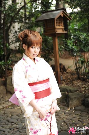 Asian Ichika in a beautiful kimono makes some soap bubbles outdoor.