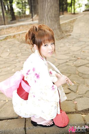 Asian Ichika in a beautiful kimono makes some soap bubbles outdoor.