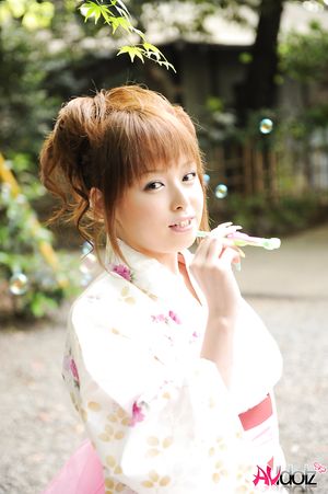 Asian Ichika in a beautiful kimono makes some soap bubbles outdoor.