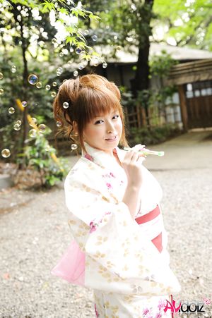 Asian Ichika in a beautiful kimono makes some soap bubbles outdoor.