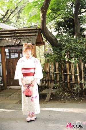 Asian Ichika in a beautiful kimono makes some soap bubbles outdoor.