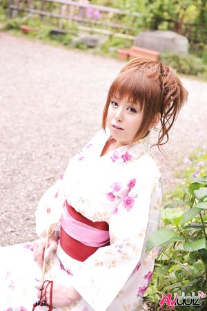 Asian Ichika in a beautiful kimono makes some soap bubbles outdoor.