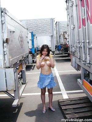 Busty japanese teen exhibs her big tits and pussy in street near trucks