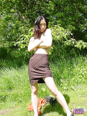 Long haired asian beauty shows her round tits in forest here