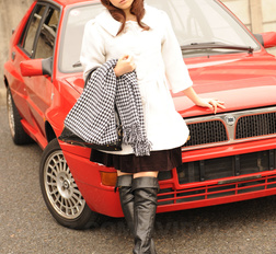 Asian Yuko Morita in white coat and long boots poses in her car.