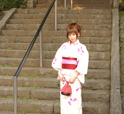 Asian Ichika in a beautiful kimono makes some soap bubbles outdoor.